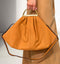 Stylish orange handbag with a gold handle and shoulder strap, showcasing a contemporary design.